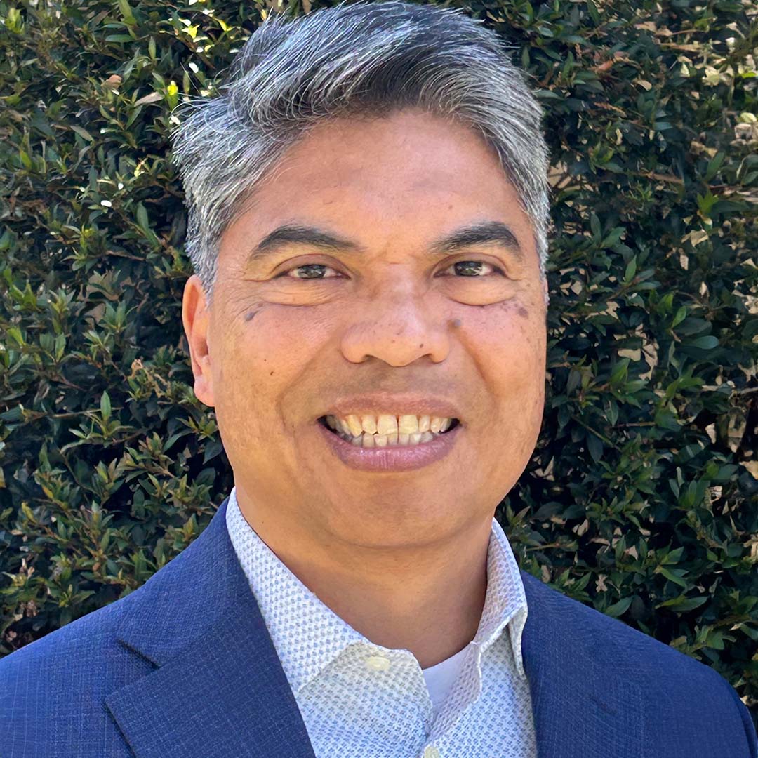 Smiling man in business attire outdoors.