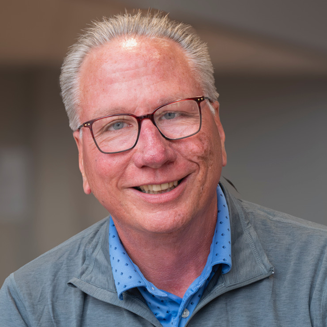 Smiling man wearing glasses and blue shirt