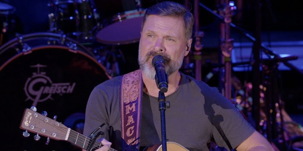 Man with guitar at a microphone