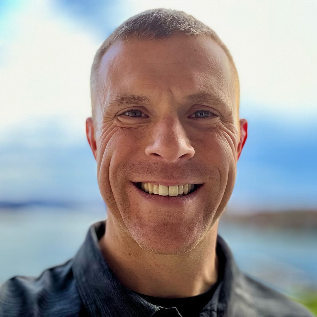 Smiling person with a blurred scenic background.