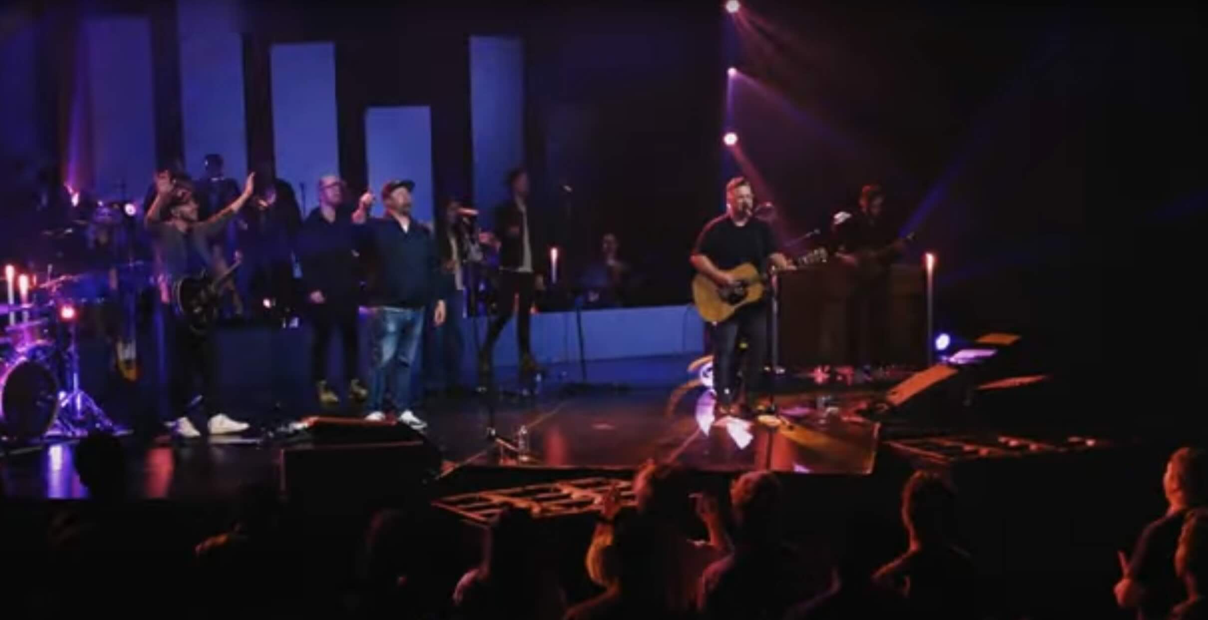 musicians on stage singing to an energetic crowd