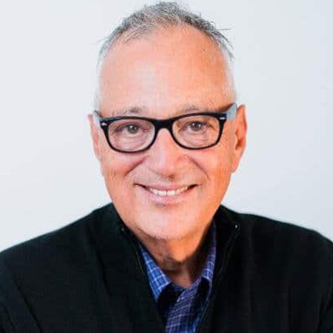 Older man wearing glasses, smiling.